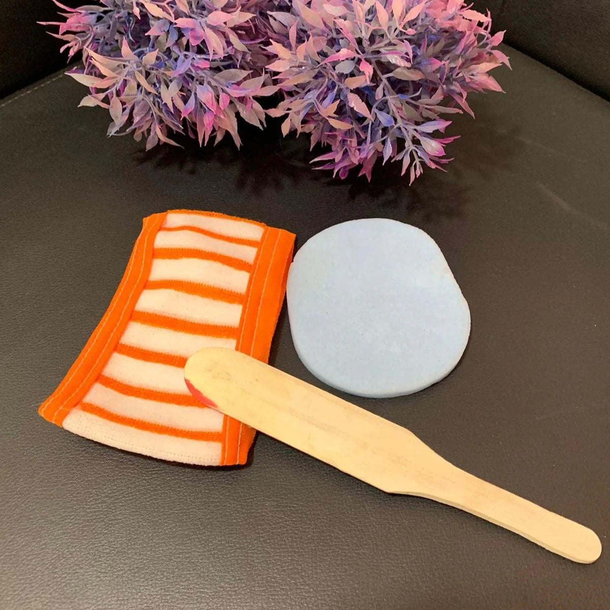 Haya by Rabi facial essentials: orange striped headband, blue sponge, and wooden spatula.